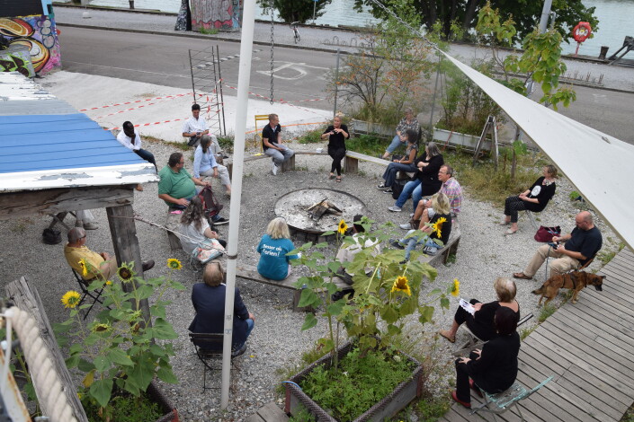 Die Teilnehmerinnen und Teilnehmer während dem Talk mit Katja Reichenstein auf dem Kiesplatz des Holzparks Klybeck.