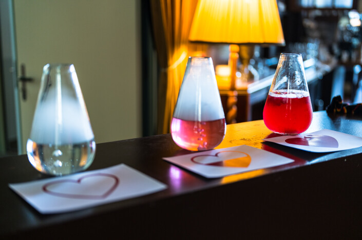 Das Bild zeigt drei Glasgefässe gefüllt mit unterschiedlich roter, dampfender Flüssigkeit, ähnlich wie im Labor.